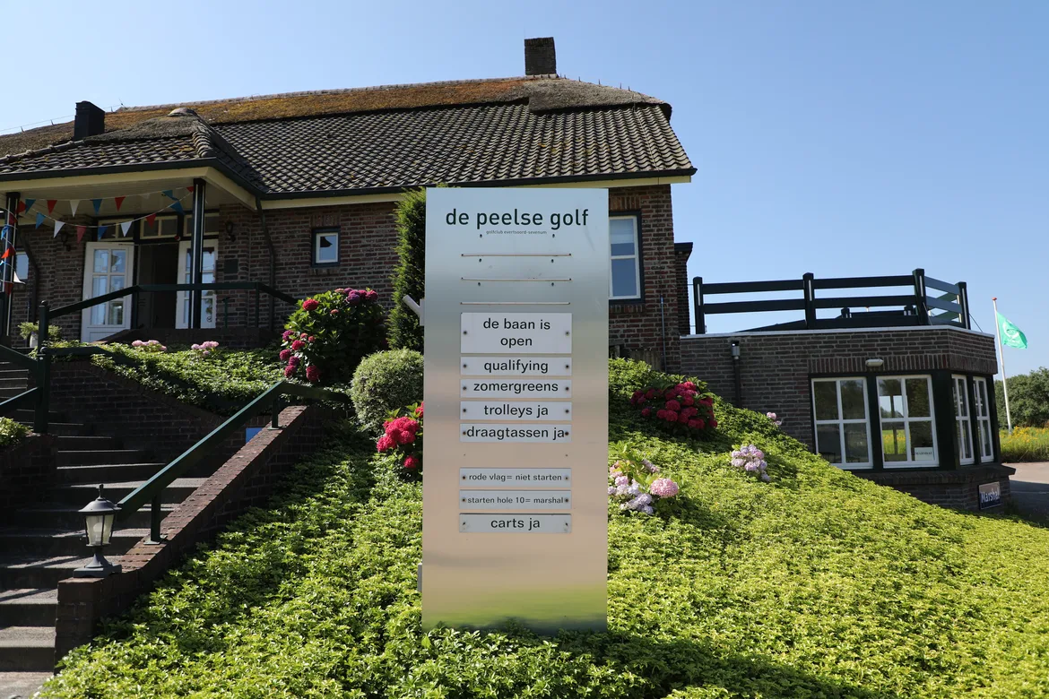 Clubhuis met informatiebord naast de ingang of de baan qualifying is en of buggies de baan in mogen
