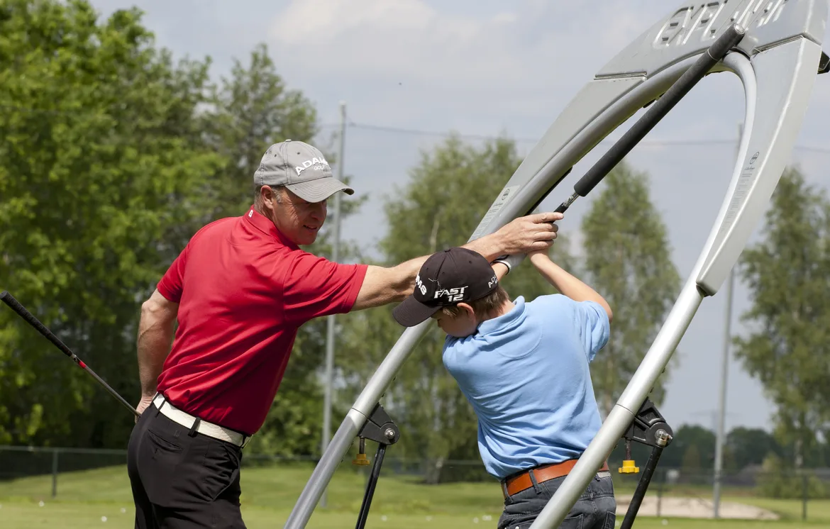 Golfpro geeft leerling aanwijzingen in de Explanar golfswing trainer