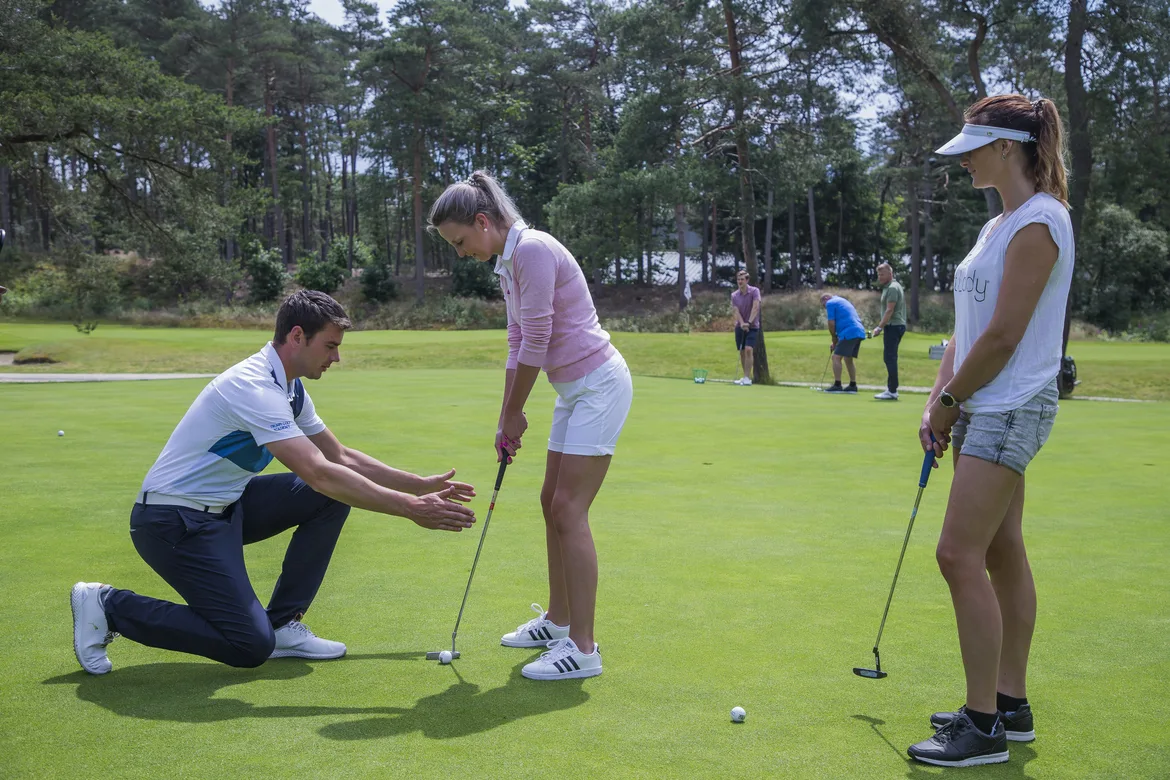 twee vrouwelijke beginnende golfers krijgen golfles van de Pro