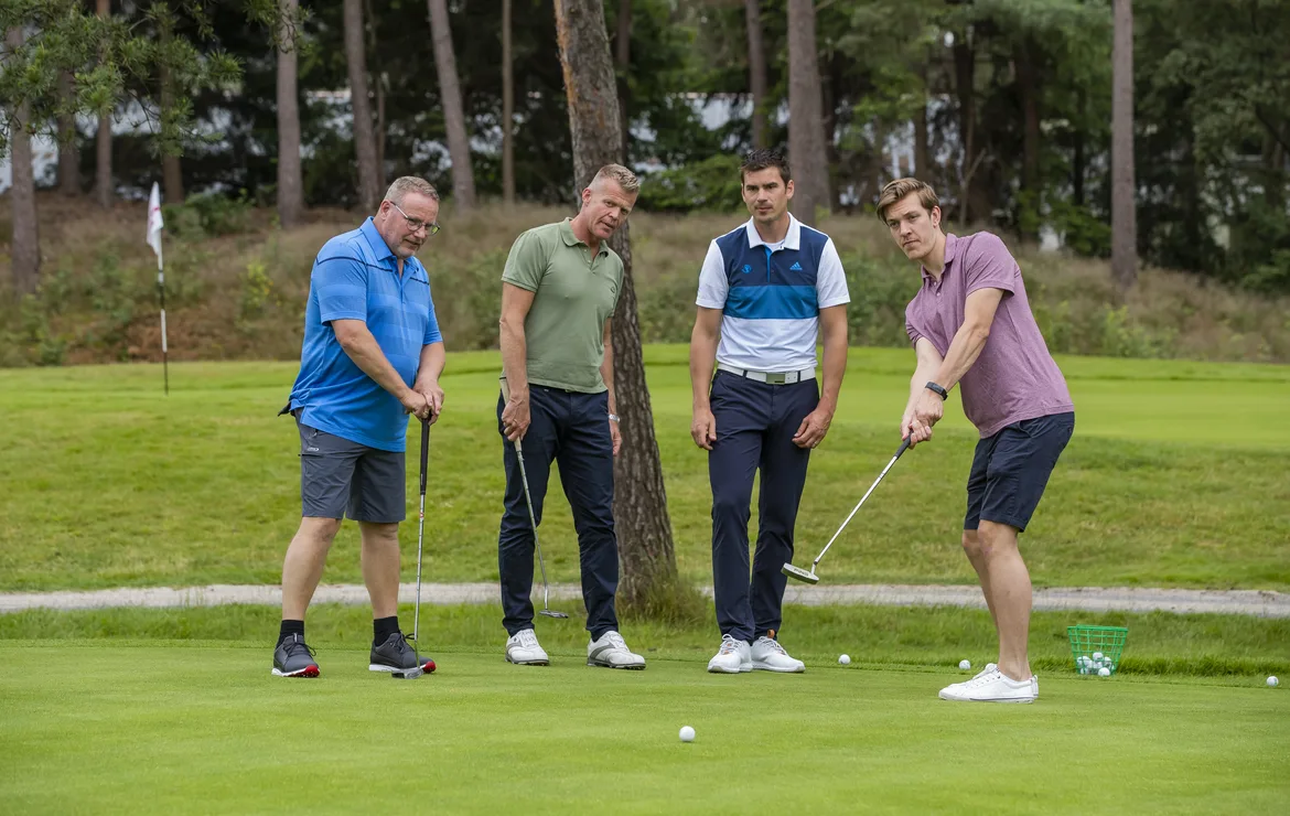 Een groep van drie mannen krijgt golfles op de green van de golfpro