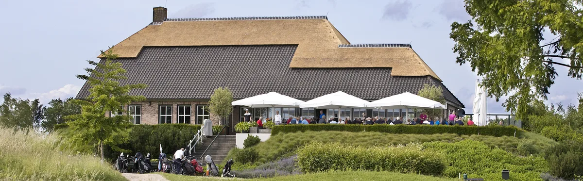 Clubhuis met vol terras gezien over het water van hole 9