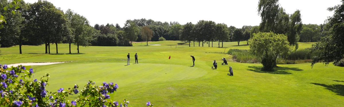 Hole 14 met drie golfers op de green